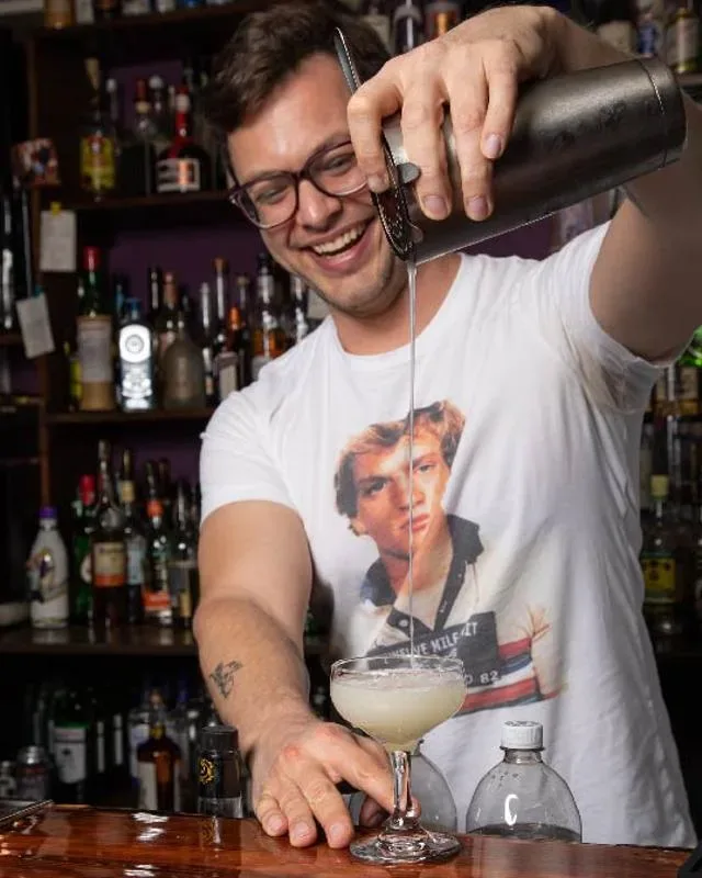 A bartender pouring a cocktail from a shaker