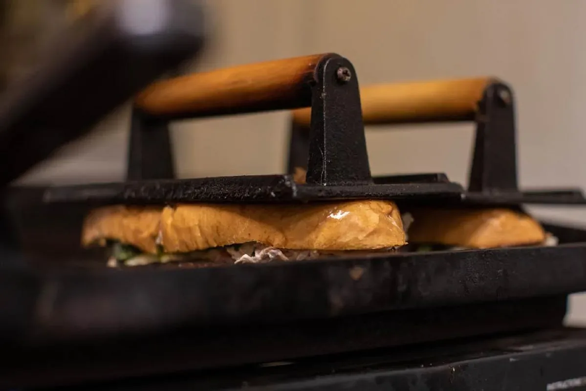 A pressed sandwich under cast-iron weights on the griddle